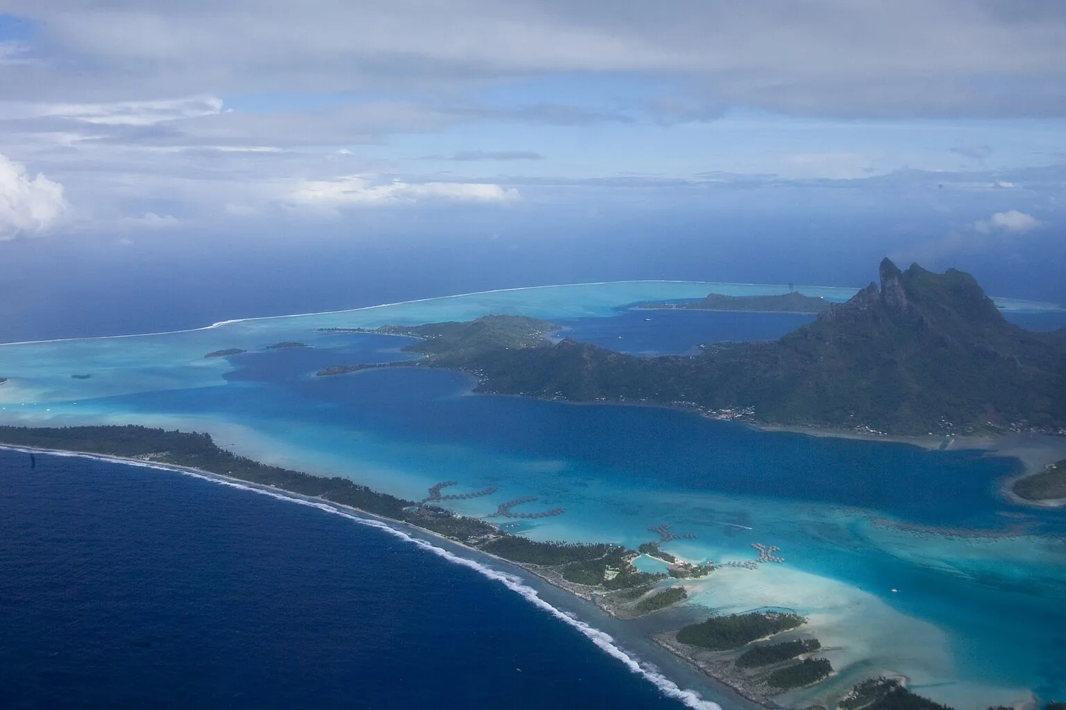 Vue aérienne de Bora-Bora : lagon turquoise, récif-barrière, bungalows sur pilotis et mont Otemanu